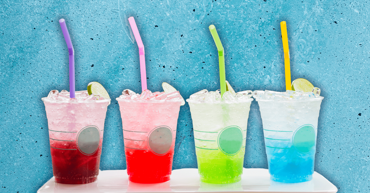 Four multicolored drinks in to-go cups with colorful straws.