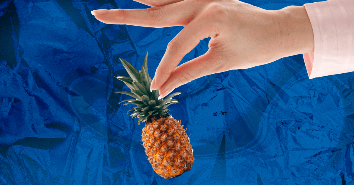 Pinched fingers hold a comically small pineapple by its leaves.